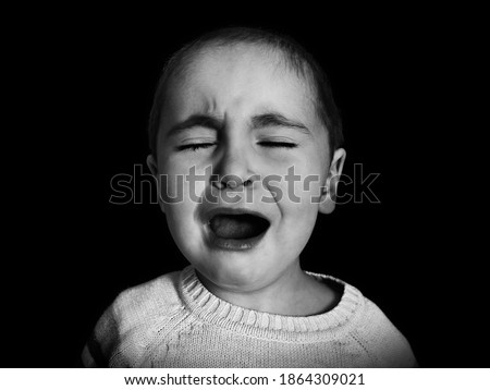
one year old girl with short hair cries uncontrollably in monochrome. Concept of anxiety, depression, childhood problems, emotions.  Royalty-Free Stock Photo #1864309021