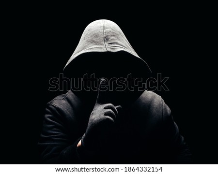 Photo of a scary horror man in hoodie showing silence hand sign in dark. Royalty-Free Stock Photo #1864332154