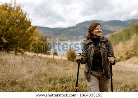 Woman standing in the middle of field, using two sticks.