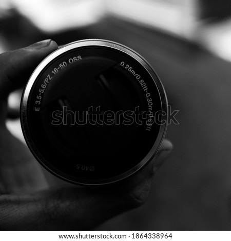 bokeh of the hand holding the camera lens. shows the front side which contains the inscription of the specifications. Photo in black and white