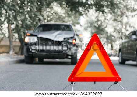 Red emergency stop triangle sign on road in car accident scene. Broken SUV car on road at traffic accident. Car crash traffic accident on city road after collision