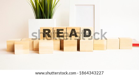 Wooden cubes with letters on a white table. The word is READ. White background.