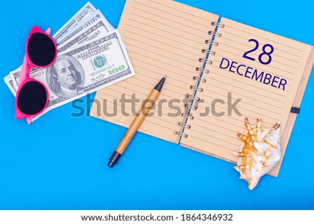 December 28. 28th day of December. Travel plan flat design with written date notepad, pen, glasses, money dollars and seashell on blue background. Winter month, day of the year, calendar concept