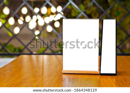 Tablet with empty space for text. Blank or layout for design. Mockup for advertising. White plate on a wooden table. Blurred bar interior on background.