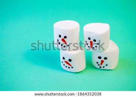 marshmallow snowmen ride on a sled on a turquoise background in close-up Christmas decorations