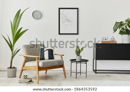Modern retro concept of home interior with design grey armchair, coffee table, commode, plants, mock up poster map, carpet and personal accessoreis. Stylish home decor of living room.
