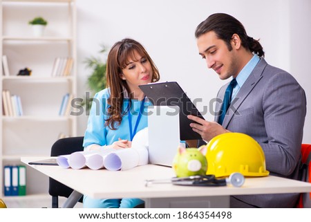 Young businessman and female doctor discussing construction proj