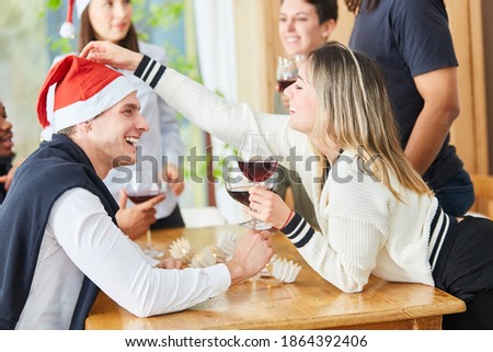 Laughing friends have fun and celebrate Christmas together with red wine at home