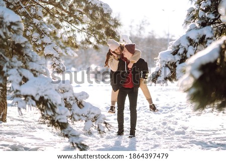 Young couple on winter holiday in a snowy forest. Happy man and woman having fun and laughing outdoors in winter. People, season, travel, love and leisure concept.