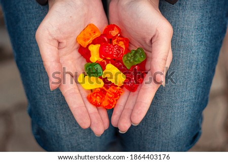 Bright and colorful gummy bears in young woman's hands