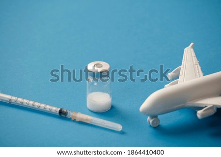 vaccine canister with syringe and white plane, blue background
