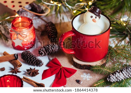 Chocolate snowman melting in warm milk, decorated in holiday spirit
