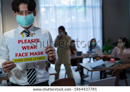 A businessman wearing a surgical mask puts an open sign warning "Please wear face mask", reopening business to adapt to the new normal in preventing the spread of the COVID-19 coronavirus.