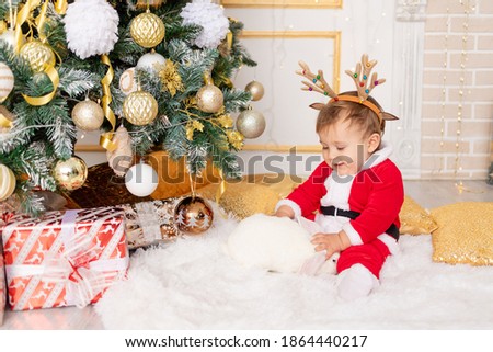 a child in a Santa costume sits at the Christmas tree with a rabbit, the concept of new year and Christmas