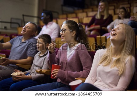 Cheerful parents with tween children watching comedy in cinema. Family leisure and entertainment concept