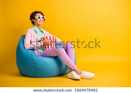 Full length body size photo girl 3d glasses watching movie eating pop corn in beanbag isolated on bright yellow color background copyspace