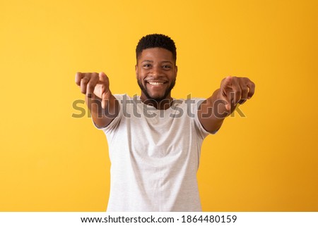 Photo of happy young african  looking at the camera while pointing to you.