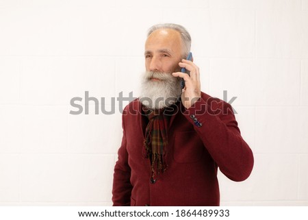 Happy trendy bearded old man talking on phone. Smiling grandfather having conversation using smartphone