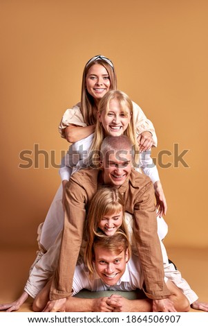 portrait of happy group of caucasian youth having fun in studio with brown background, beautiful people in trendy wear are cheerful. models, people, emotions concept