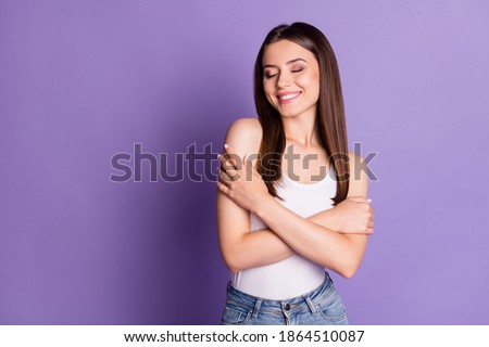 Photo of adorable smiling young woman wear casual white outfit embrace herself closed eyes isolated violet color background