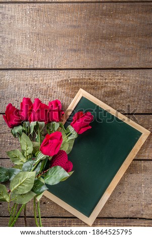 Red rose flowers bouquet with red heart on wooden background. Valentine's day greeting card background. Copy space Top view