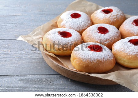 Hanukkah doughnuts with jelly and sugar powder on grey wooden table, closeup