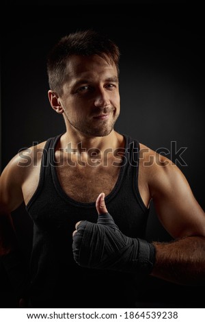 Handsome fit smiling bearded man showing Ok gesture on black background