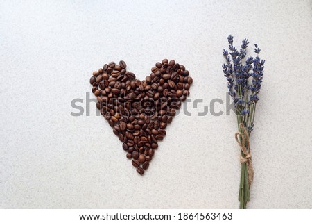 Heart of coffee beans with a lavender bouquet on a gray background, top view, close-up, space for text
