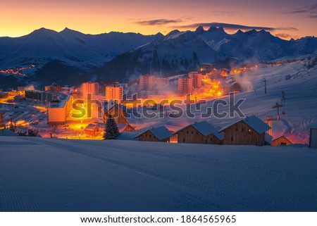 Picturesque winter ski resort with cute buildings at dawn. Wonderful resort and ski slopes at sunrise, La Toussuire, Rhone Alps, France, Europe Royalty-Free Stock Photo #1864565965