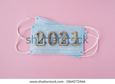Christmas 2021. Coronavirus new year minimal concept. Flat lay with face masks, metal numbers on pink background. top view, copy space