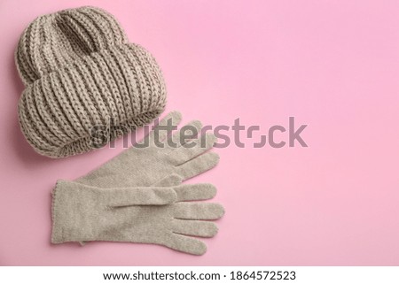 Woolen gloves and hat on pink background, flat lay. Space for text