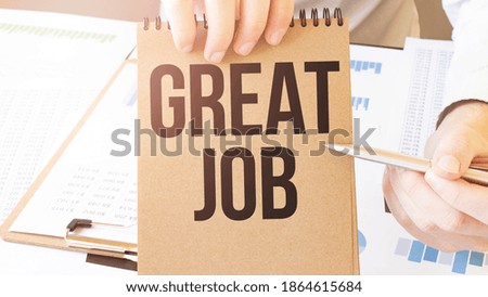 Text GREAT JOB on brown paper notepad in businessman hands on the table with diagram. Business concept