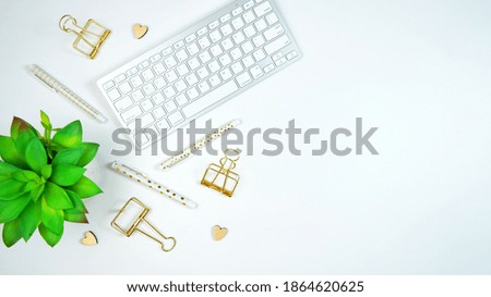 Stylish white and gold theme desktop workspace with keyboard, notebooks and smart phone. Top view blog hero header creative composition flat lay.