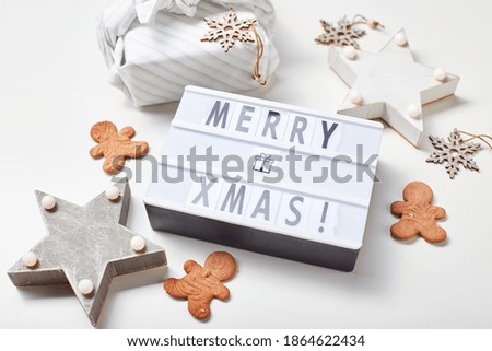 New Year or Christmas composition, flat lay, top view. Light box inscription Merry Christmas, gifts in Japanese furoshiki style and gingerbread cookies, copy space.