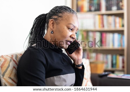 Woman living with HIV working from her home living room and talking on her smartphone Royalty-Free Stock Photo #1864631944