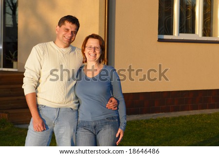 Husband and wife standing near house