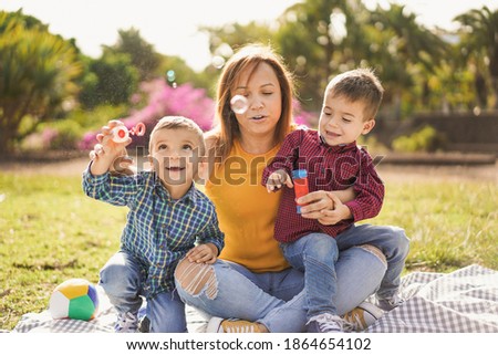 Mother have playful time with twin sons in nature park with soap bubbles - Mother and children love