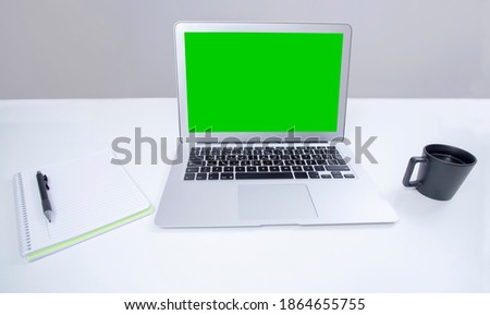 laptop computer green screen over office desk