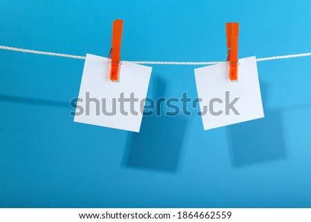 sheets of paper are hung with a clothespin on a rope