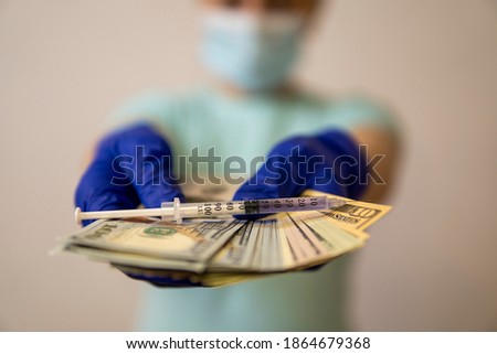 hands in medical gloves keep money on which the syringe lies. coronavirus vaccine cost concept