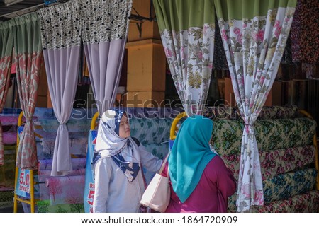 Mother and daughter  choosing a curtain in  textiles shop