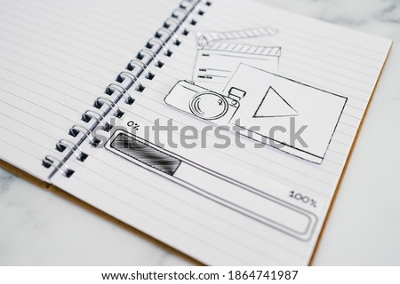 planning content for social media conceptual image, notebook with photo and video icon next to text and progress bar loading