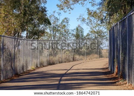 View of part of the fenced area of the trail on top of the dam wall at Lake Miramar in San Diego, California.
