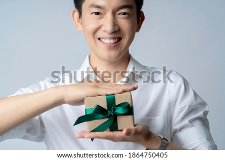 happiness asian male mature adult wearing white shirt hand hold present gift box smile with cheerful giving wrap present box to camera point of view white background festive concept