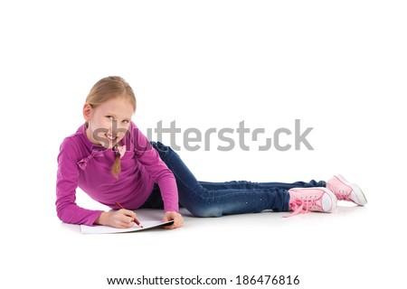 Cute girl drawing. Young girl laying on the floor and drawing something on the sheet of paper. Full length studio shot isolated on white.