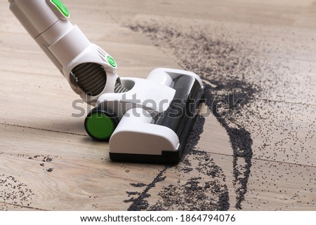 A man uses a bagless vertical cordless vacuum cleaner to clean the floor. Royalty-Free Stock Photo #1864794076