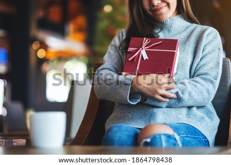 Closeup image of a beautiful young asian woman holding a red present box 