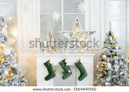 Christmas decor of the white fireplace in the living room. Fairy stars and socks for Santa Claus Royalty-Free Stock Photo #1864840960