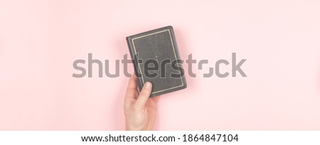 Closed black book Bible on the table. On a pink background. Holy bible