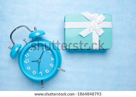 A picture of aluminium box with alarm clock on blue background.  Surprise gift box concept.